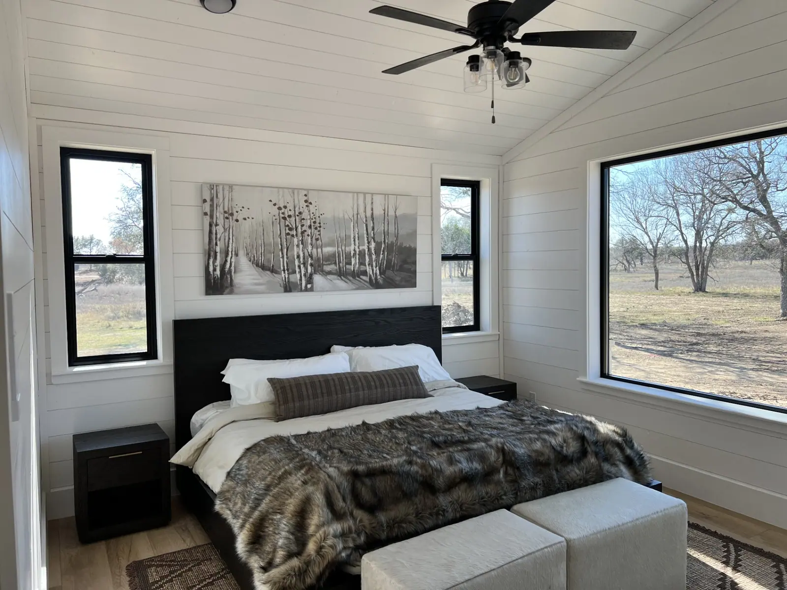 Guest bedroom with vaulted shiplap ceiling and black-framed windows