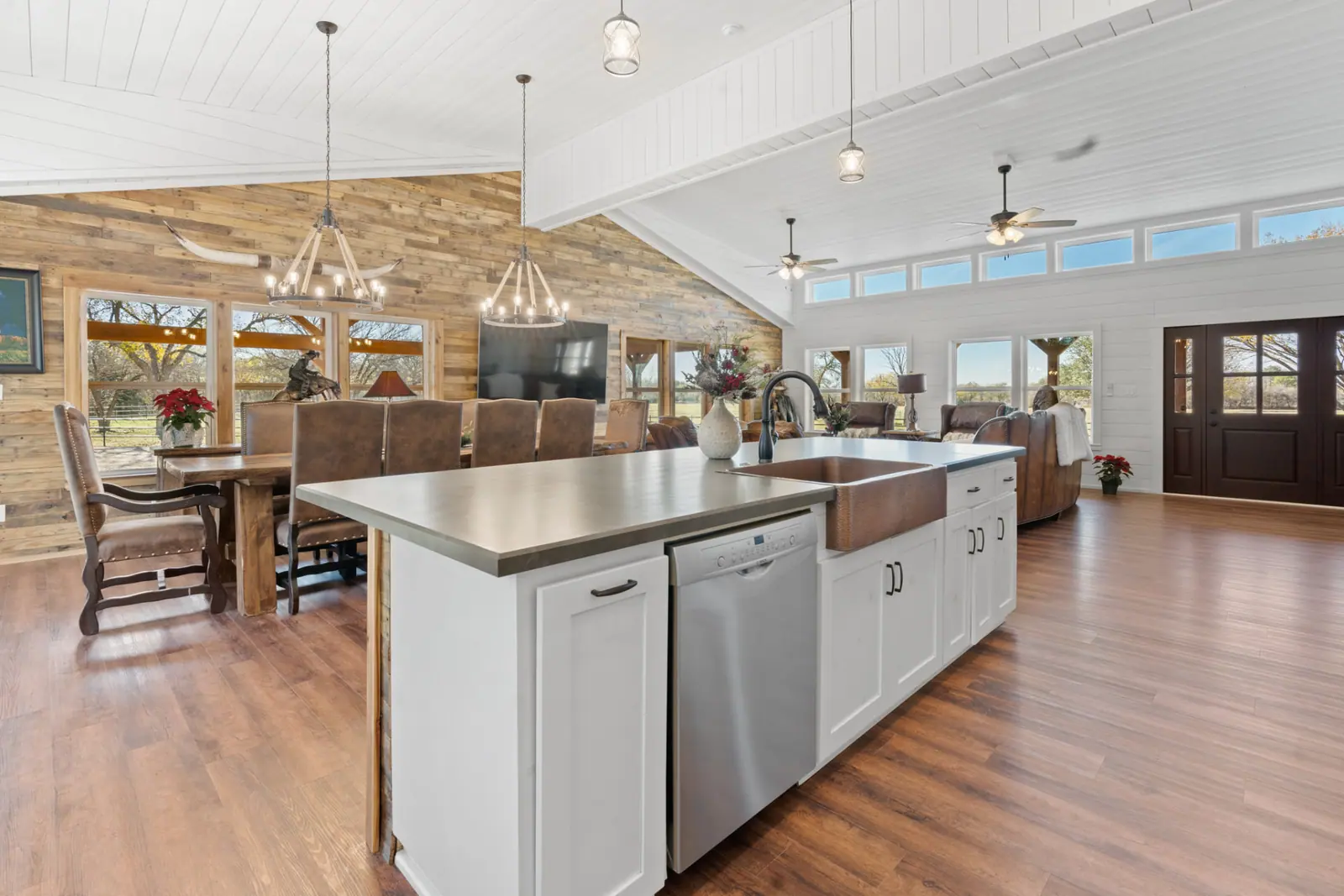 Kitchen island and dining area under vaulted shiplap ceiling with chandeliers