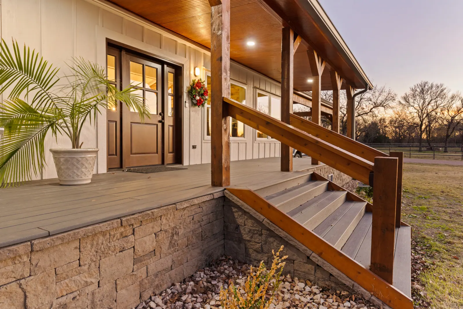 Front entry porch at sunset with stone skirting and wood steps