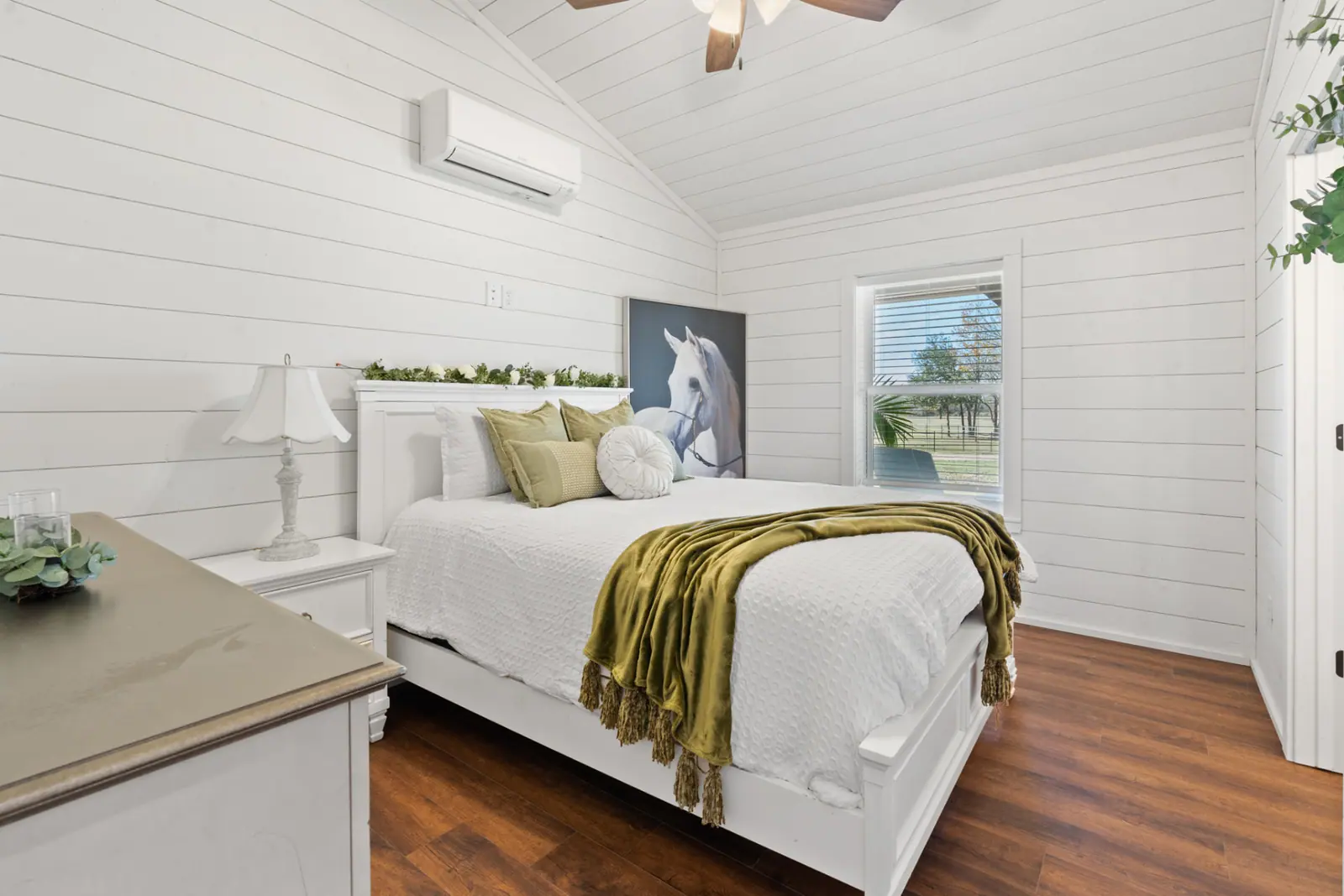 Bedroom with white shiplap walls, equestrian art and green accents