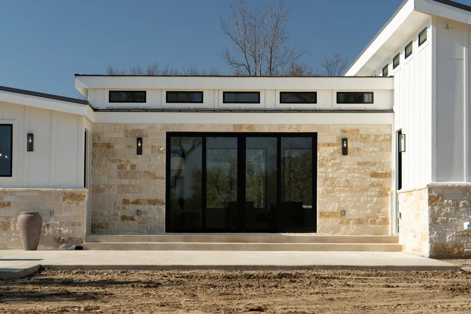 Limestone entry elevation with black sliding glass doors and clerestory windows