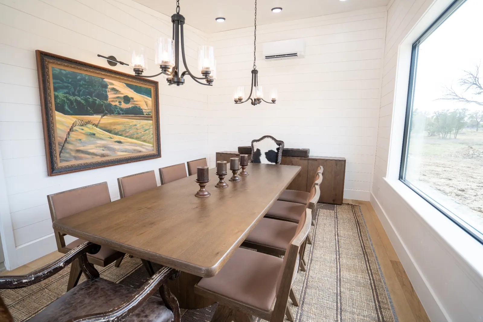 Formal dining room with long oak table and iron chandeliers