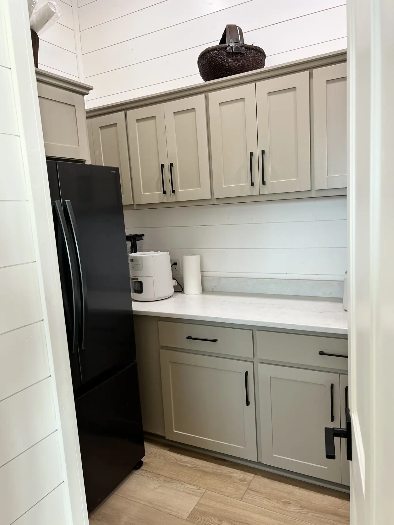 Walk-in butler pantry with sage cabinetry and marble counters