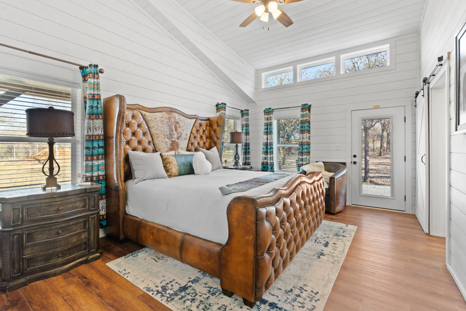 Primary bedroom with tufted leather bed and vaulted shiplap ceiling