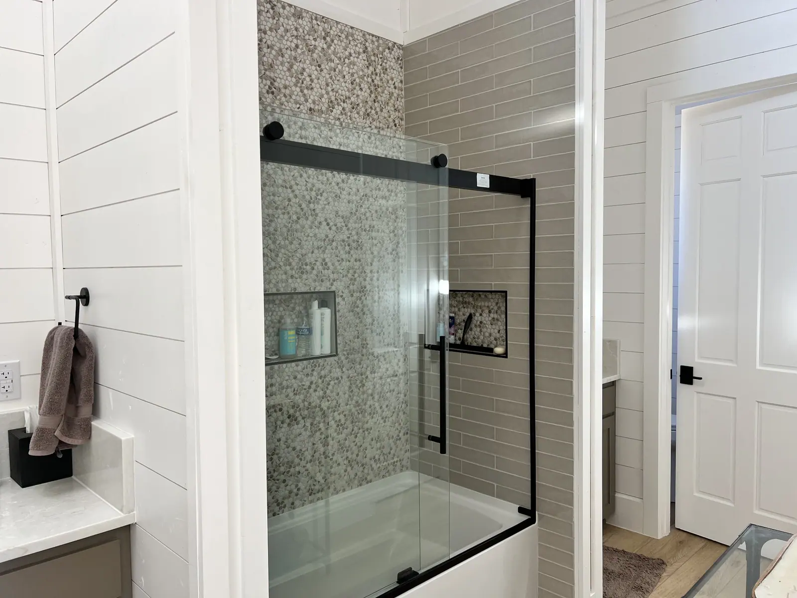Guest bath with tiled tub-shower, penny-round accent wall and black fixtures