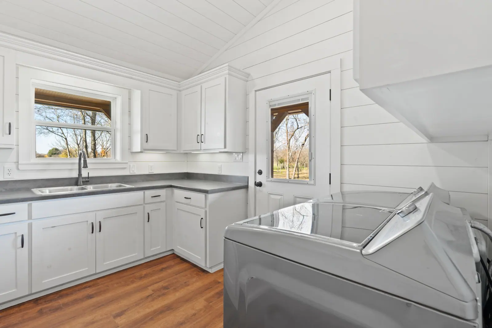 Laundry room with white cabinetry, utility sink and exterior door